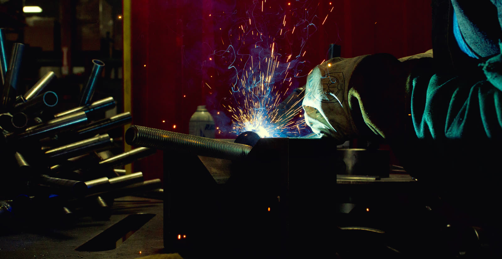 Welding an Active Force frame against a red shop wall